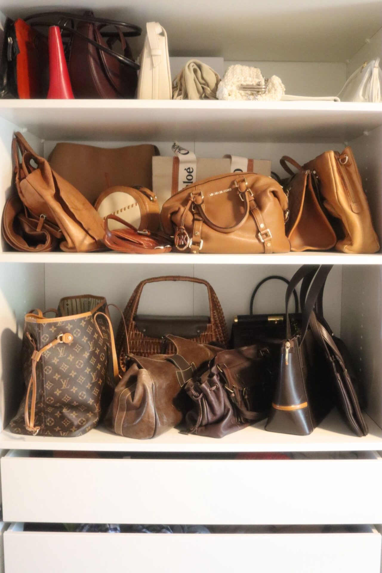 Bolsas no guarda-roupa separadas por cor: vermelhas e brancas em cima, caramelo no meio e marrons embaixo